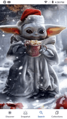 a baby yoda wearing a santa hat is holding a mug of hot chocolate