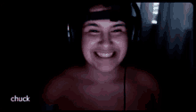 a shirtless man wearing headphones is smiling in a dark room and the word chuck is on the bottom right