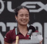 a woman is holding a trophy and a bottle of champagne in front of a sign that says plex open