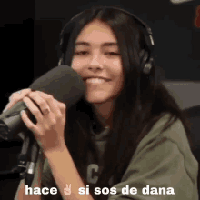 a woman wearing headphones is smiling while holding a microphone with the words hace si sos de dana written below her