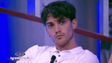 a man sitting in front of a microphone with #grandefratello on the bottom right