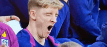 a soccer player is yawning while sitting in the stands during a match .