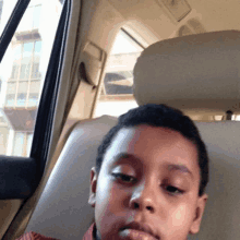 a young boy is sitting in the back seat of a car looking at the camera