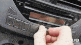 a person pressing a button on a car radio that says volume push pwr
