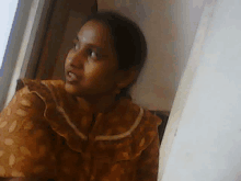 a woman in a floral shirt is sitting in front of a window