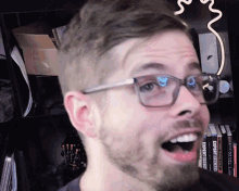 a man wearing glasses and a beard stands in front of a shelf full of books including one called expert soccer