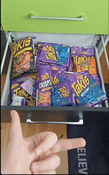 a person is pointing at a drawer full of takis