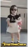 a little girl wearing sunglasses is standing in front of a sign that says star tamil chat.in