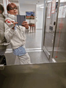 a woman taking a picture of herself in an elevator with a sign on the wall that says ' elevator '