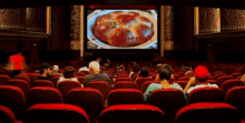 people are watching a movie in a theater with an arrow pointing to a plate of food on a screen