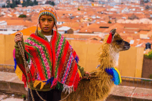 a boy in a colorful poncho holding a llama