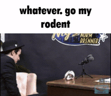 a man sitting in front of a microphone with the words " whatever go my rodent " written above him
