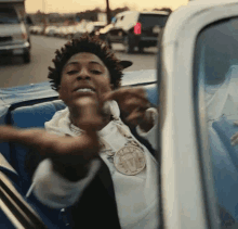 a young man is sitting in the back seat of a car giving the middle finger .