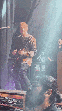 a man playing a guitar on a stage in front of a sign that says ' a few dollars ' on it