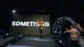 a wrestler in front of a screen that says something