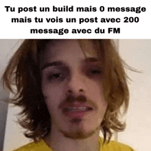 a man with long hair and a beard is wearing a yellow shirt and has a message on his face .