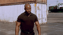 a man in a black shirt stands in front of a shipping container that says ' container ' on it