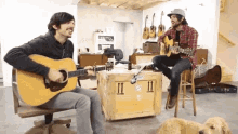 two men are playing guitars in a room with a box that says 11 on it