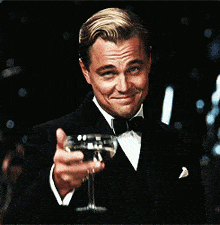 a man in a tuxedo holds up a glass of wine