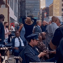 a group of people are gathered on a sidewalk in front of a street sign that says ' one way '