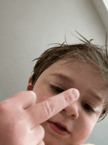 a young boy with a finger on his nose