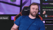 a man wearing headphones and a blue shirt is sitting in front of a screen that says code squad