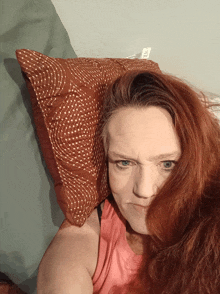 a woman with red hair and a pillow on her head