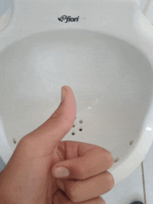 a person giving a thumbs up in front of a urinal that says fiori