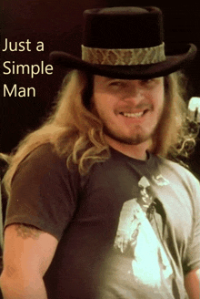 a man with long hair wearing a cowboy hat and smiling