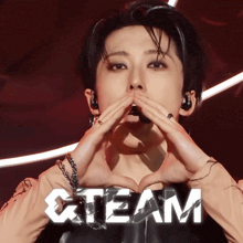 a person making a heart shape with their hands with the word team behind them