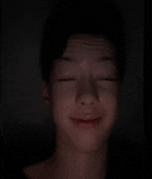 a young boy is making a funny face with his eyes closed in the dark .