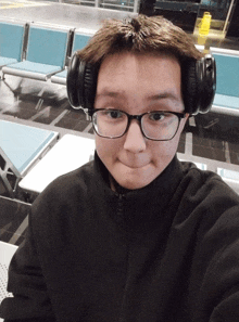 a young man wearing headphones and glasses looks at the camera