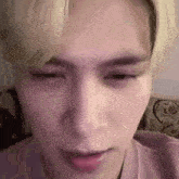 a close up of a person 's face with their eyes closed and a pink shirt on .