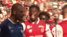 a group of soccer players are standing in front of a crowd and one of their shirts says ' reebok ' on it