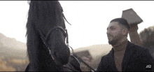 a man standing next to a black horse with the letters ar on the bottom left