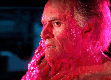 a close up of a man 's face with pink liquid on it