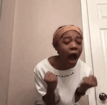 a woman is standing in front of a door with her mouth open and her fists in the air .