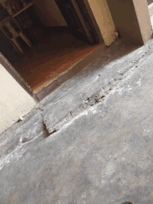 a concrete floor with a crack in it and a doorway in the background