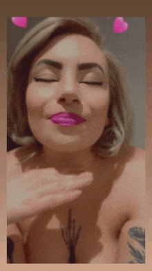 a woman with purple lipstick and a tattoo on her chest is blowing a kiss