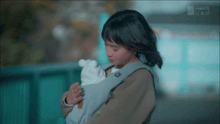 a woman is carrying a baby in a carrier with insight on the bottom right
