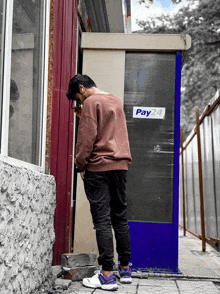 a man standing in front of a pay24 kiosk