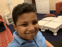 a boy in a blue shirt is smiling in front of a white table