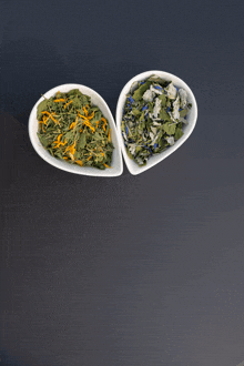 two bowls filled with different types of leaves and flowers on a table