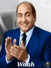 a man wearing a blue suit and tie is clapping his hands