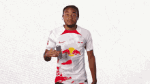 a man in a red bull shirt holds up a can of soda