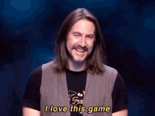 a man with long hair and a beard is smiling and saying i love this game