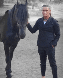 a man in a suit stands next to a horse