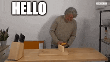 a man is standing in front of a wooden table with a knife block and the word hello above him