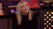 a blonde woman sitting in front of a shelf with a book titled " the way of the world "