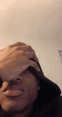 a man covering his face with his hand while wearing a hat